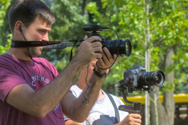 Kyiv Ukrayna - 31 Ağustos 2021: İki kameraman şehir parkında bir sahne çekiyor. Pro ekipmanlar titremeden yüksek kaliteli video yapmaya yardımcı olur.