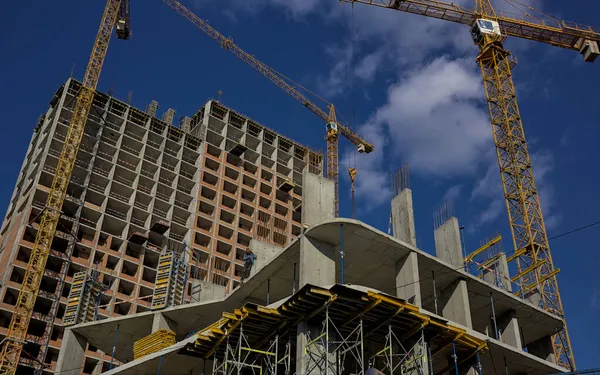 Kyiv Ukrayna - 15 Ekim 2021: Yüksek irtifada bir inşaat işçisi bir inşaat sahasının en üst katında çalışıyor. Modern apartmanlar ve yeni bir konut kompleksi inşaatı. Mavi gökyüzü.