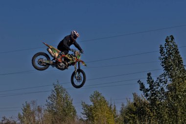 Kyiv, Ukrayna - 9 Ekim 2021: Mavi gökyüzünün arka planına karşı motorsikletle aşırı atlama. Aktif aşırı dinlenme. Yüksek uçan motosiklet yarışçısı.