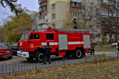 Kyiv, Ukrayna - 30 Ekim 2021: büyük kırmızı itfaiye arabası ve itfaiye ve acil durum merdivenleri şehir caddesinde. Yangın koruma giysisi giymiş bir itfaiyeci. Gerçek bir yangının söndürülmesi..