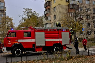 Kyiv, Ukrayna - 30 Ekim 2021: büyük kırmızı itfaiye arabası ve itfaiye ve acil durum merdivenleri şehir caddesinde. Yangın koruma giysisi giymiş bir itfaiyeci. Gerçek bir yangının söndürülmesi..