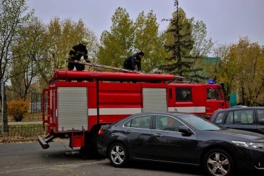 Kyiv, Ukrayna - 30 Ekim 2021: büyük kırmızı itfaiye arabası ve itfaiye ve acil durum merdivenleri şehir caddesinde. Yangın koruma giysisi giymiş bir itfaiyeci. Gerçek bir yangının söndürülmesi..