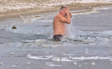 Kyiv, Ukrayna - 19 Ocak 2022: Adam kış günü buzlu suya daldı. Geleneksel vaftiz töreni. Buzlu Dnipro Nehri 'ndeki Epifani bayramı.