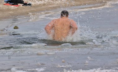 Kyiv, Ukrayna - 19 Ocak 2022: Adam kış günü buzlu suya daldı. Geleneksel vaftiz töreni. Buzlu Dnipro Nehri 'ndeki Epifani bayramı.