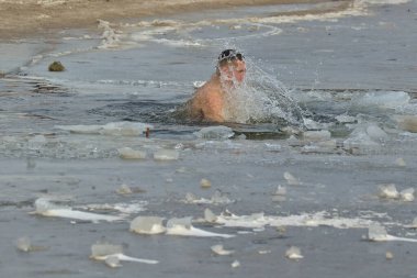 Kyiv, Ukrayna - 19 Ocak 2022: Adam kış günü buzlu suya daldı. Geleneksel vaftiz töreni. Buzlu Dnipro Nehri 'ndeki Epifani bayramı.