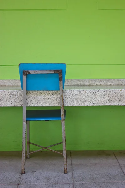 Chaise étudiante bleue à côté du mur lumineux vert — Photo