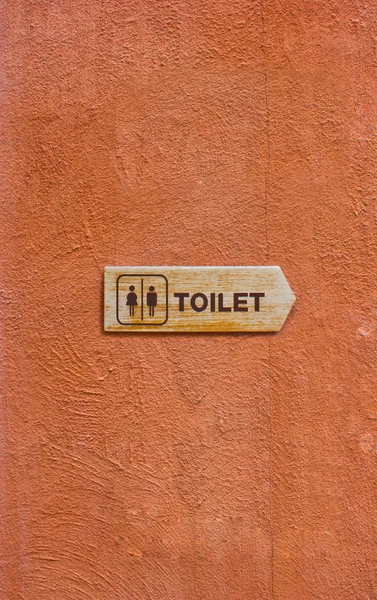 Hölzernes Toilettenschild an der orangen Wand — Stockfoto