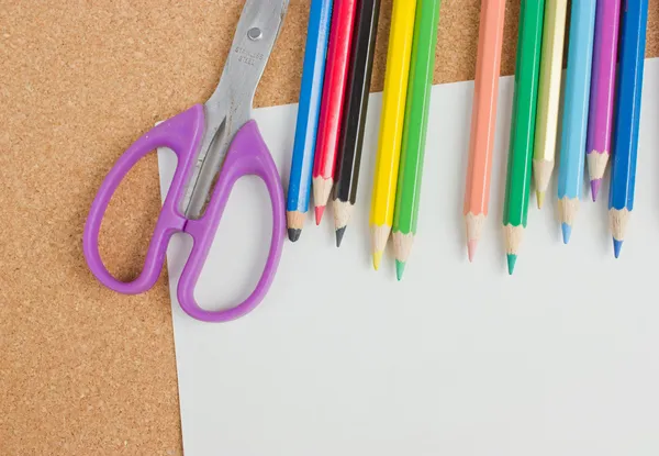 Цветные карандаши, чистые ножницы и бумага на борту . — стоковое фото
