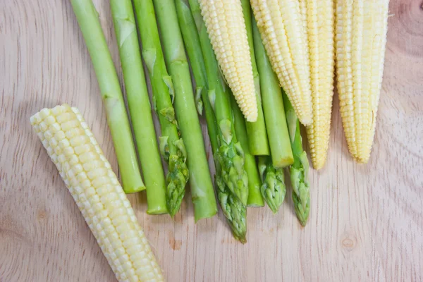 Asparagus and baby corn on chopping block. — Stock Photo, Image