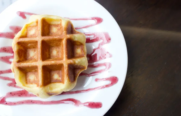 Close up of waffle on white plate with grape sauce. — Stock Photo, Image