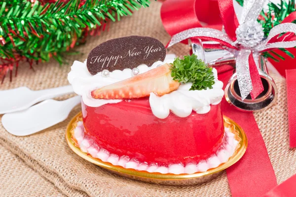 Strawberry cake with bells and ribbon on burlap. — Stock Photo, Image