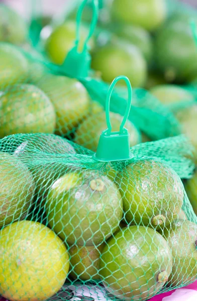 Limas com rede de plástico verde — Fotografia de Stock