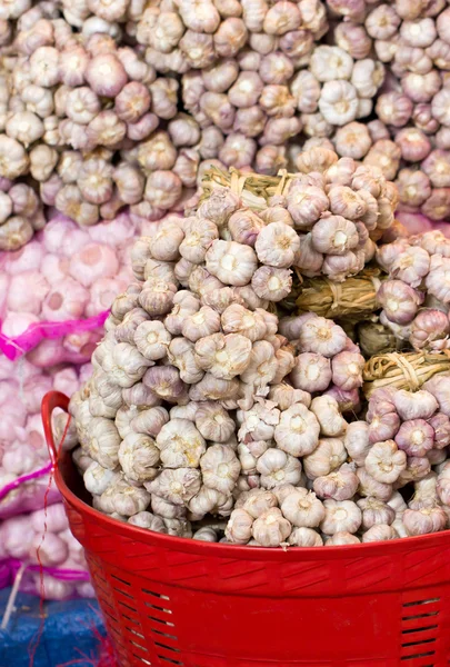 Garlic bunch in red plastic basket. — Stock Photo, Image