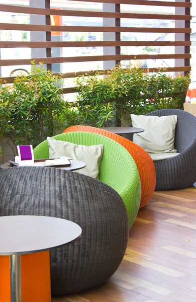 Farbenfrohe moderne geflochtene ovale Stühle mit Tischen. — Stockfoto