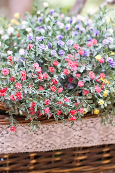 Small artificial flowers in weave basket. — Stock Photo, Image