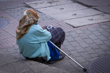 Yaşlı kadın sokakta yalvarıyor.