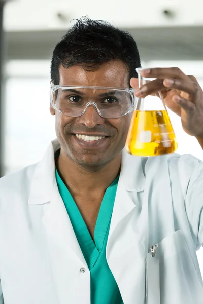 Male scientist looking at beaker of liquid