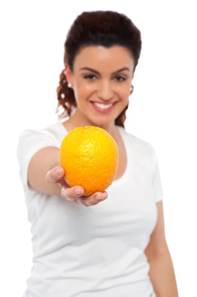 Sonriente hermosa mujer que le ofrece una naranja — Foto de Stock