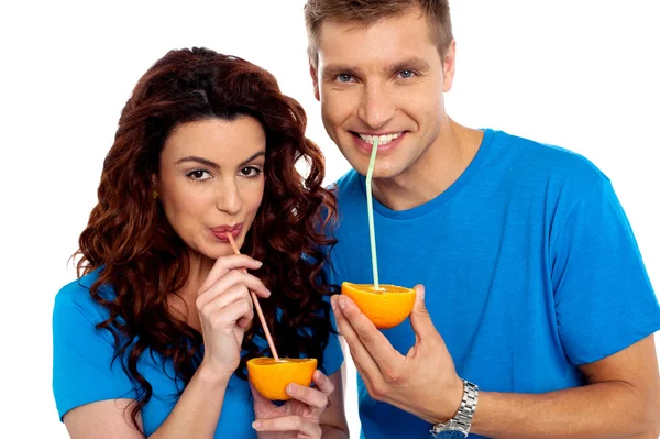 Closeup of couple cuddling and sipping orange juice — Stock Photo, Image