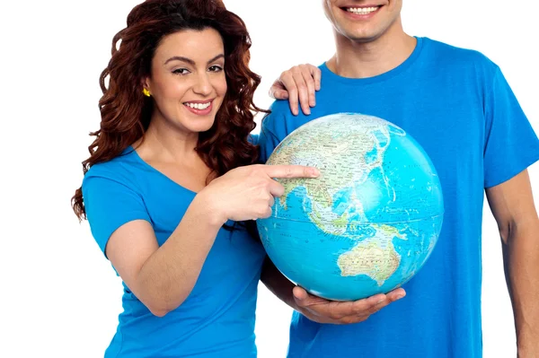 Woman pointing at China on globe while man holds it — Stock Photo, Image