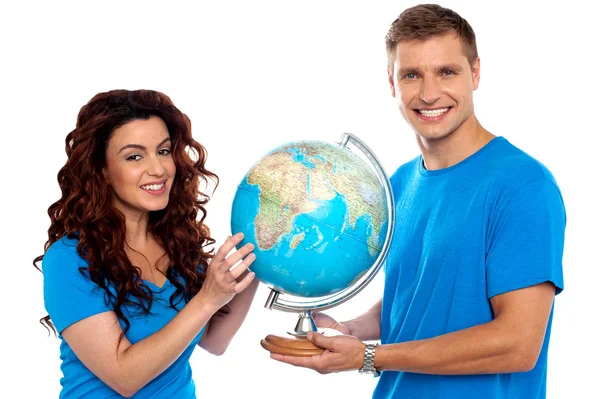 Joyful couple holding globe and smiling at camera — Stock Photo, Image