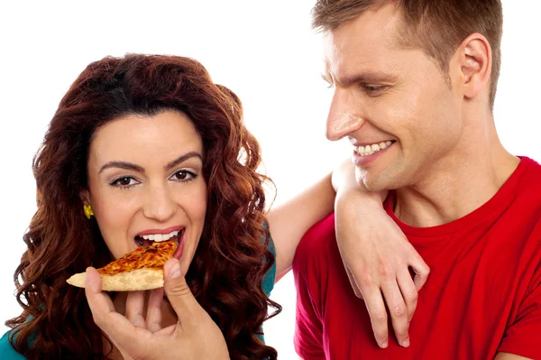 Girl enjoying pizza piece shared by her boyfriend — Stock Photo, Image