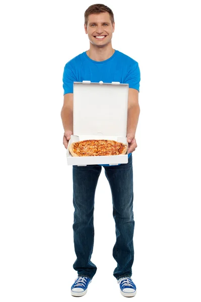 Chico casual mostrando pizza deliciosa recién horneada — Foto de Stock