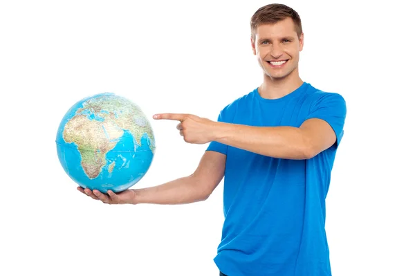 Handsome young caucasian pointing at globe — Stock Photo, Image