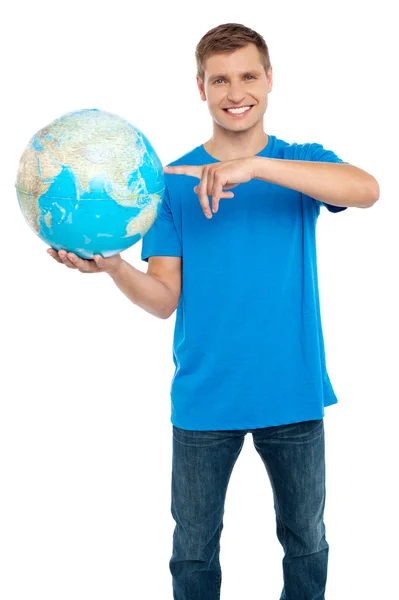 Smart guy pointing at the globe. Dressed in casuals — Stock Photo, Image