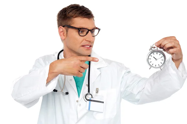 Schokkend jonge dokter wijzend op alarm clock — Stockfoto