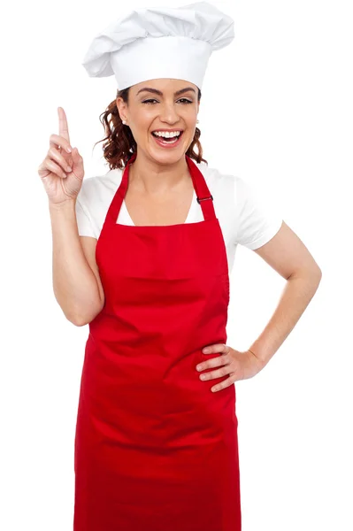 Beautiful smiling female chef indicating upwards Royalty Free Stock Images