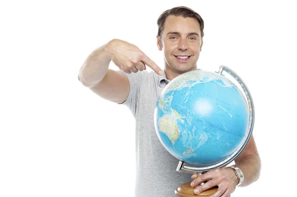 Homem segurando globo e apontando sobre ele — Fotografia de Stock