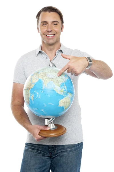 Isolated young man pointing at globe — Stock Photo, Image