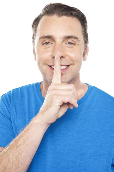 Smiling young man gesturing silence — Stock Photo, Image