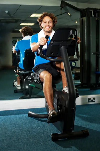 Cara inteligente trabalhando na bicicleta de exercício — Fotografia de Stock