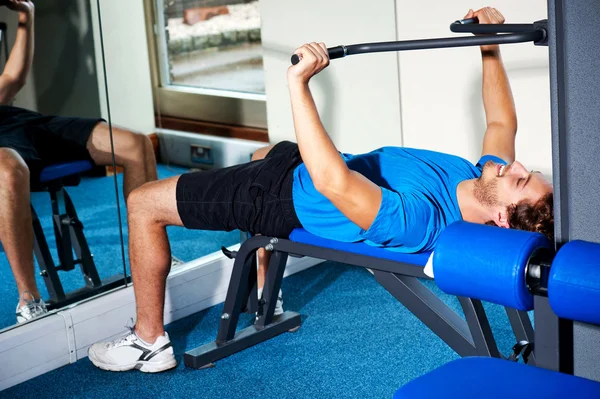 Fitness guy lying on bench and exercising — Stock Photo, Image