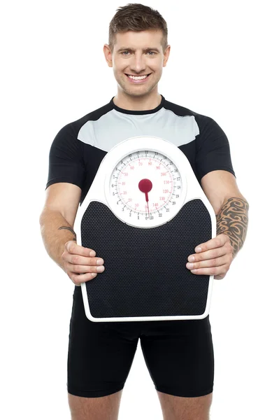 Smart young fit male showing weighing machine — Stock Photo, Image