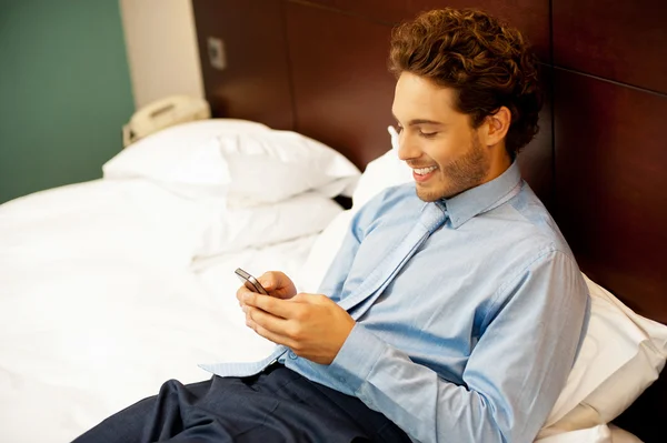 Cool chlapík čtení vtipné zprávy na jeho mobilní telefon — Stock fotografie