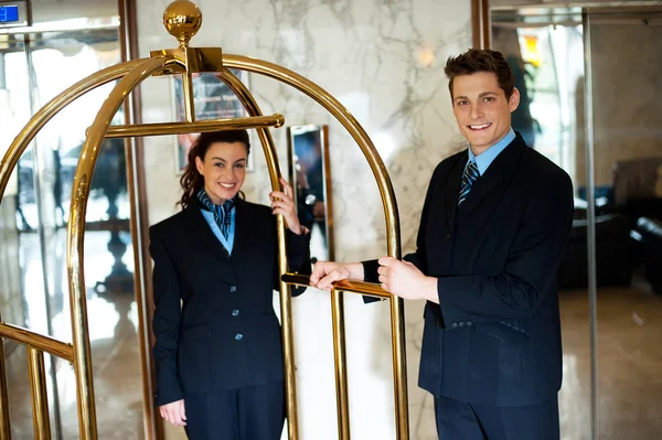 Concierges segurando o carrinho e posando — Fotografia de Stock