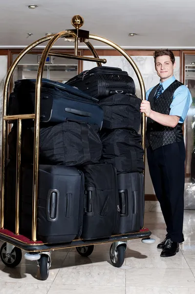 Portero con una pila de bolsas en el carrito de equipaje Fotos De Stock Sin Royalties Gratis