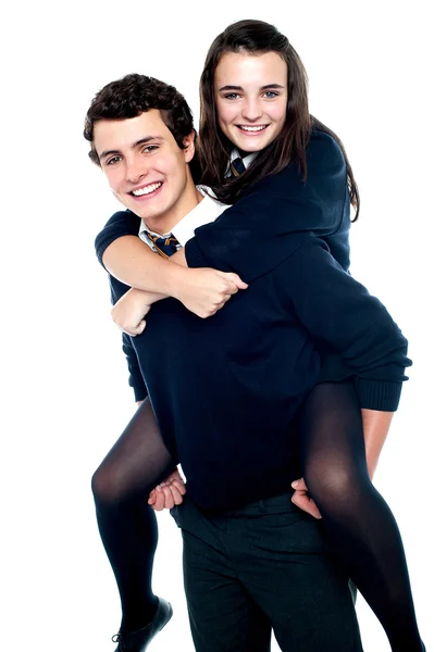 Girl riding piggyback and embracing boy tightly — Stock Photo, Image