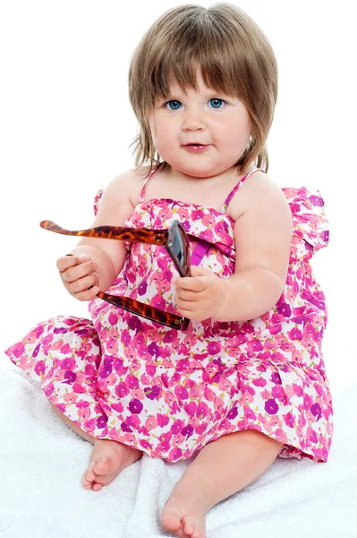 Baby girl sitting with shades in her hand — Stock Photo, Image