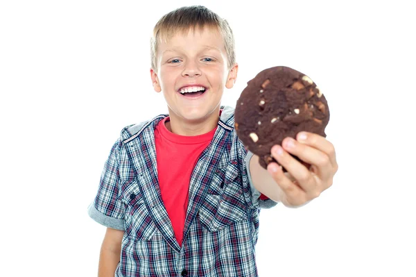 Cheerful boy offering you a chocolate cookie — Stock Photo, Image