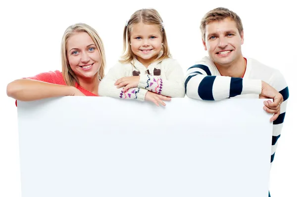 Smiling family with whiteboard in a studio — Stock Photo, Image