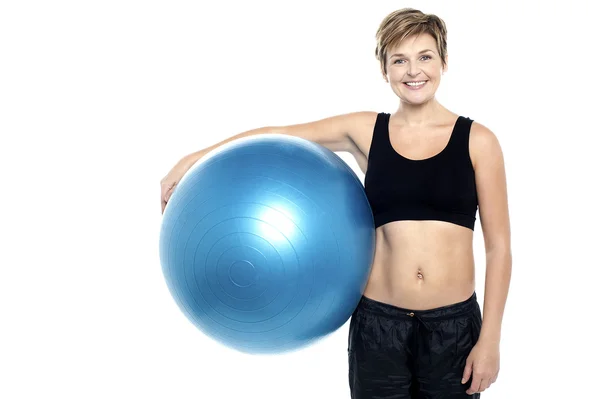 Eine attraktive, fitte Dame mit blauem Pilates Ball — Stockfoto