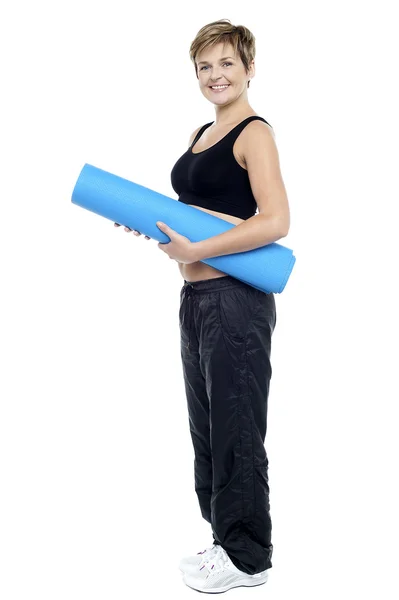 Vrouwelijke instructeur die van een blauwe yoga mat glimlachen — Stockfoto