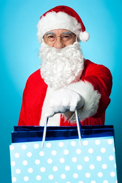 Santa bedrijf boodschappentassen in zijn uitgestrekte armen — Stockfoto