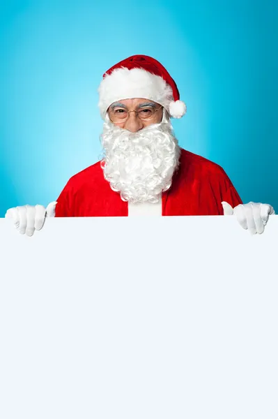 Aged Santa standing behind a blank ad board — Stock Photo, Image