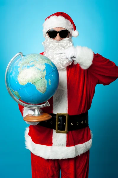 Babbo Natale elegante in tonalità scure che punta verso il globo — Foto Stock