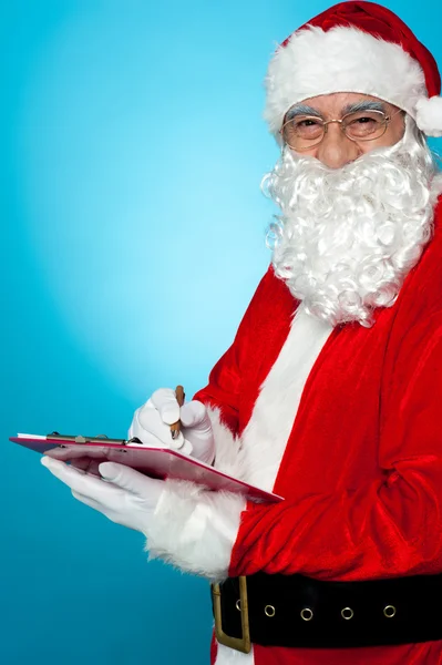 Weihnachtsmann macht sich Notizen auf der Wunschliste — Stockfoto